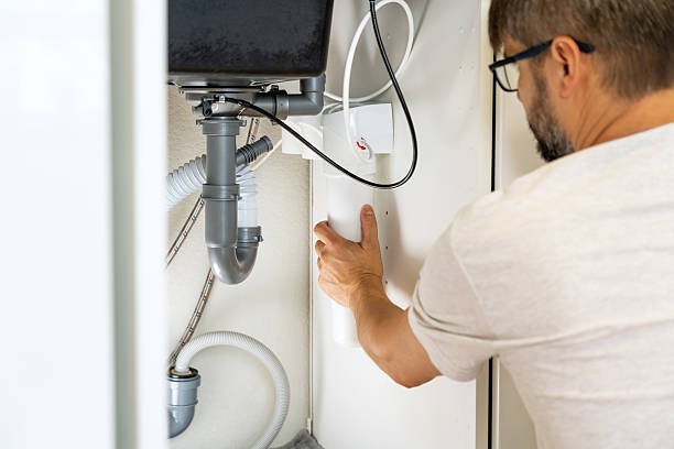 Replacement water purifier. Plumber installs water filter and changes water filter cartridges in kitchen under sink