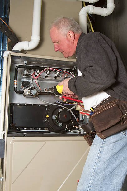 Repairman servicing or repairing basement furnace unit